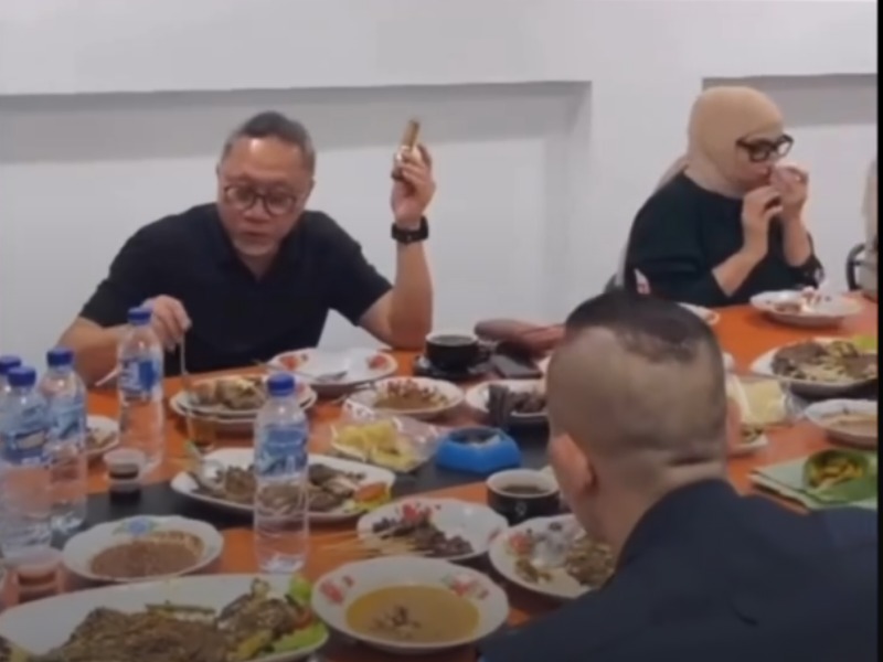 Menko Pangan Zulkifli Hasan sedang makan sambil memegang cerutu.